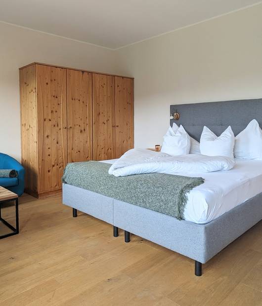 Paradiesgartl room with double bed, wardrobe, sofa and table at Naturhotel Molzbachhof.