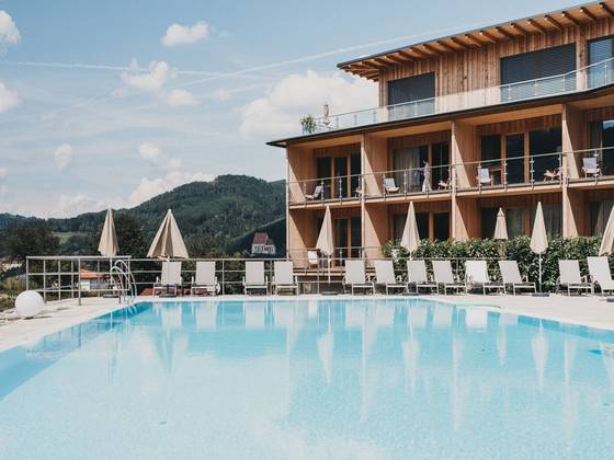 Heated pool at the Molzbachhof with a view of the wooden hotel