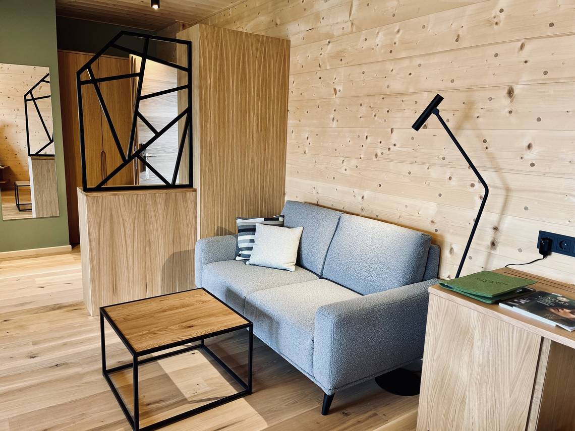 Couch with table in the Weitblick room at the Naturhotel Molzbachhof.
