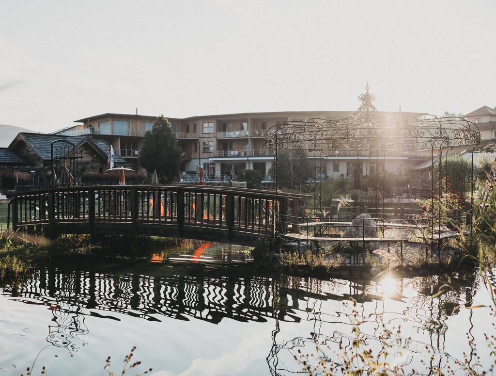 Natural bathing pond with a view of the Molzbachhof wooden hotel