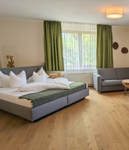 Ebenfeld room with double bed, sofa and sitting area at the Naturhotel Molzbachhof.